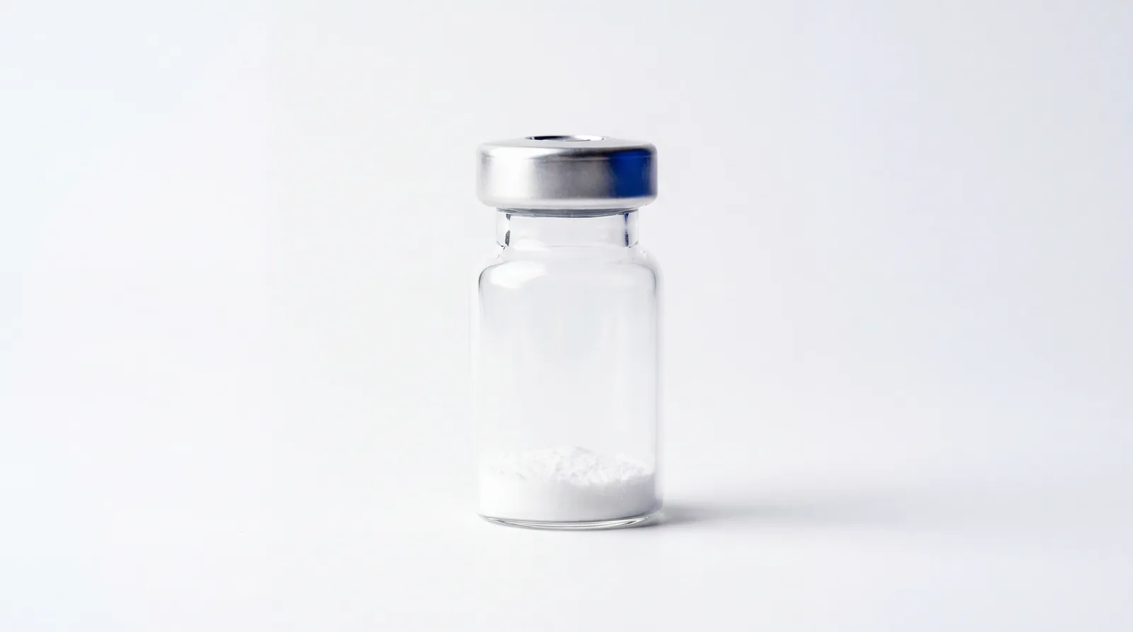 Macro close-up of a small unlabelled vial with a thin layer of white powder
